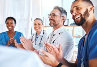 four medical personnel clapping and smiling