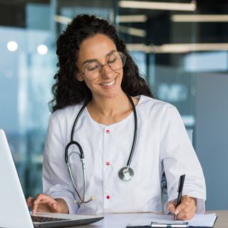 smiling medical doctor standing at a computer