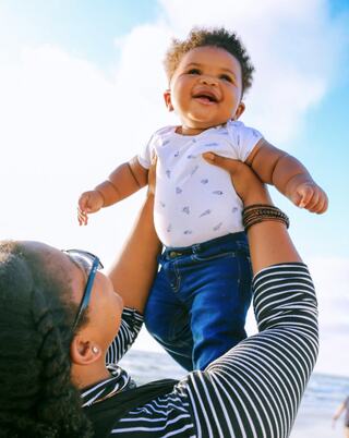 person holding a toddler up in the air in front of them