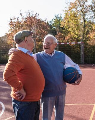 two mature men having fun on a basketball court on an autumn day